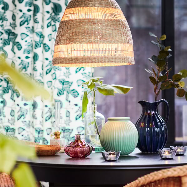 Pantalla de lámpara TORARED sobre una mesa con recipientes decorativos.