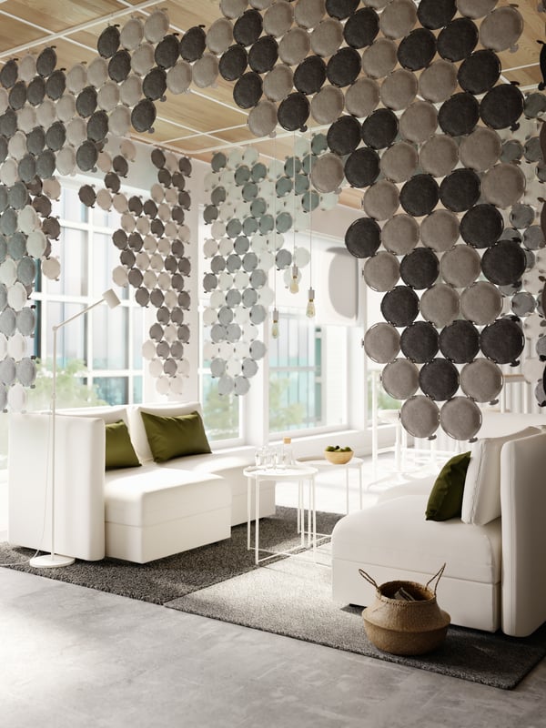 A cozy sitting area with white modular sofas and sound-absorbing panels in light and dark grey hanging from the ceiling.