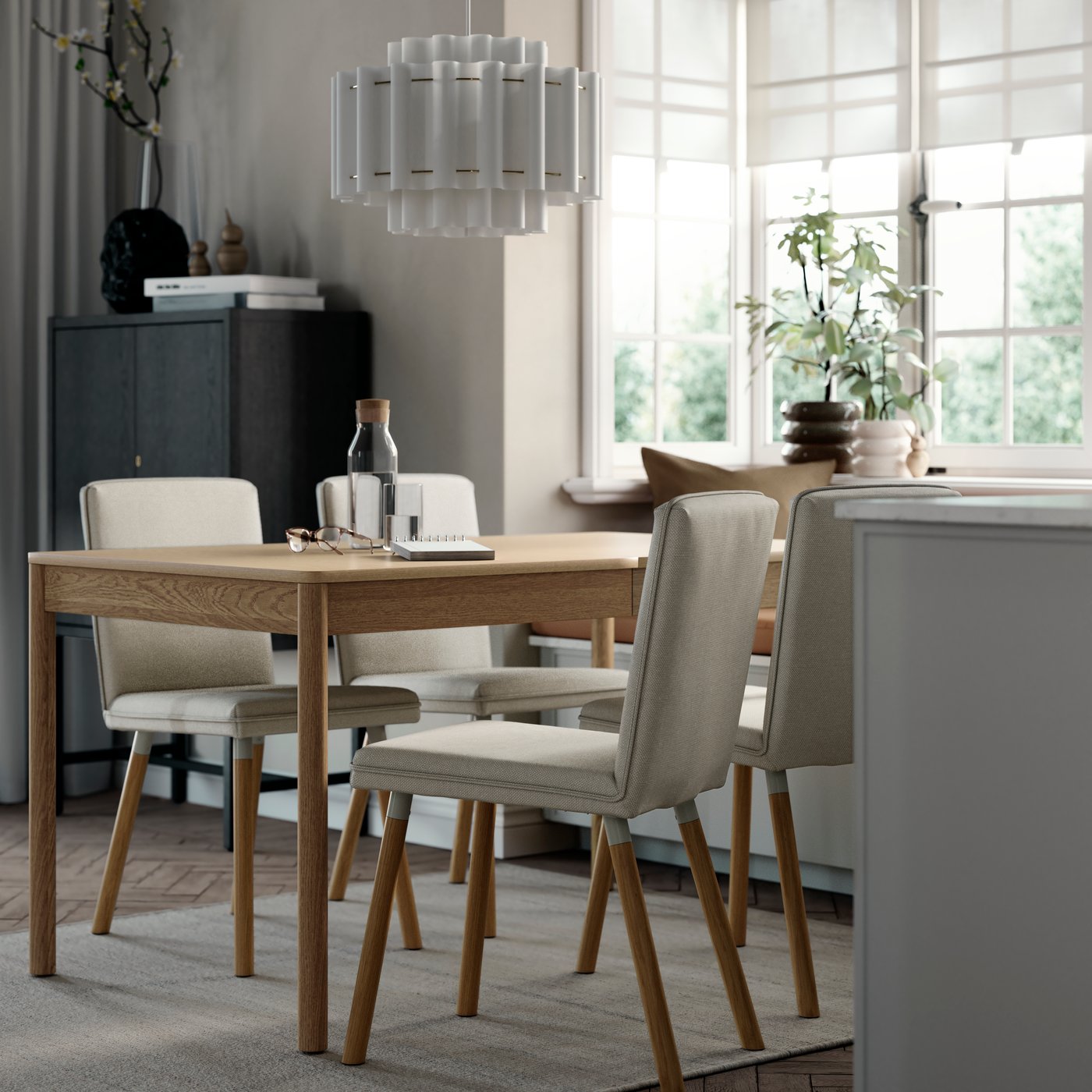 A TONSTAD extendable table in oak veneer set in a dining room with four grey chairs and natural light from windows.