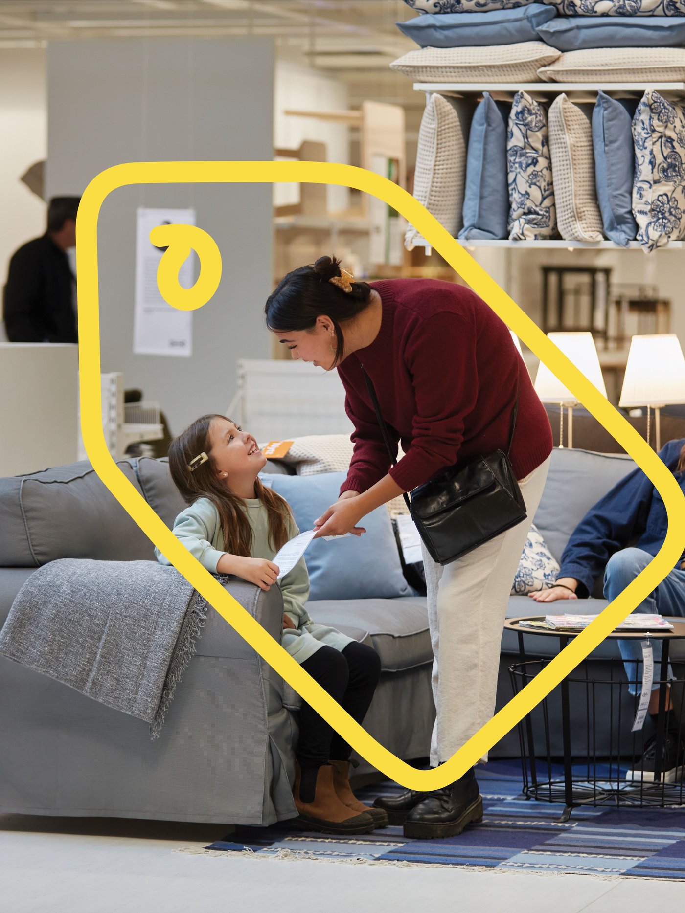 Un bambino piccolo e due adulti in un negozio IKEA stanno provando un divano grigio.