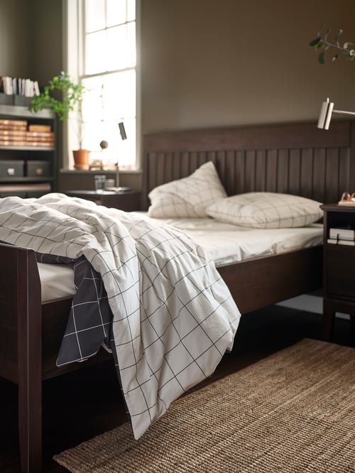 Modernes Schlafzimmer mit der VITKLÖVER Bettwäsche auf einem IDANÄS Bettgestell. Darunter ragt ein LOHALS Teppich hervor.