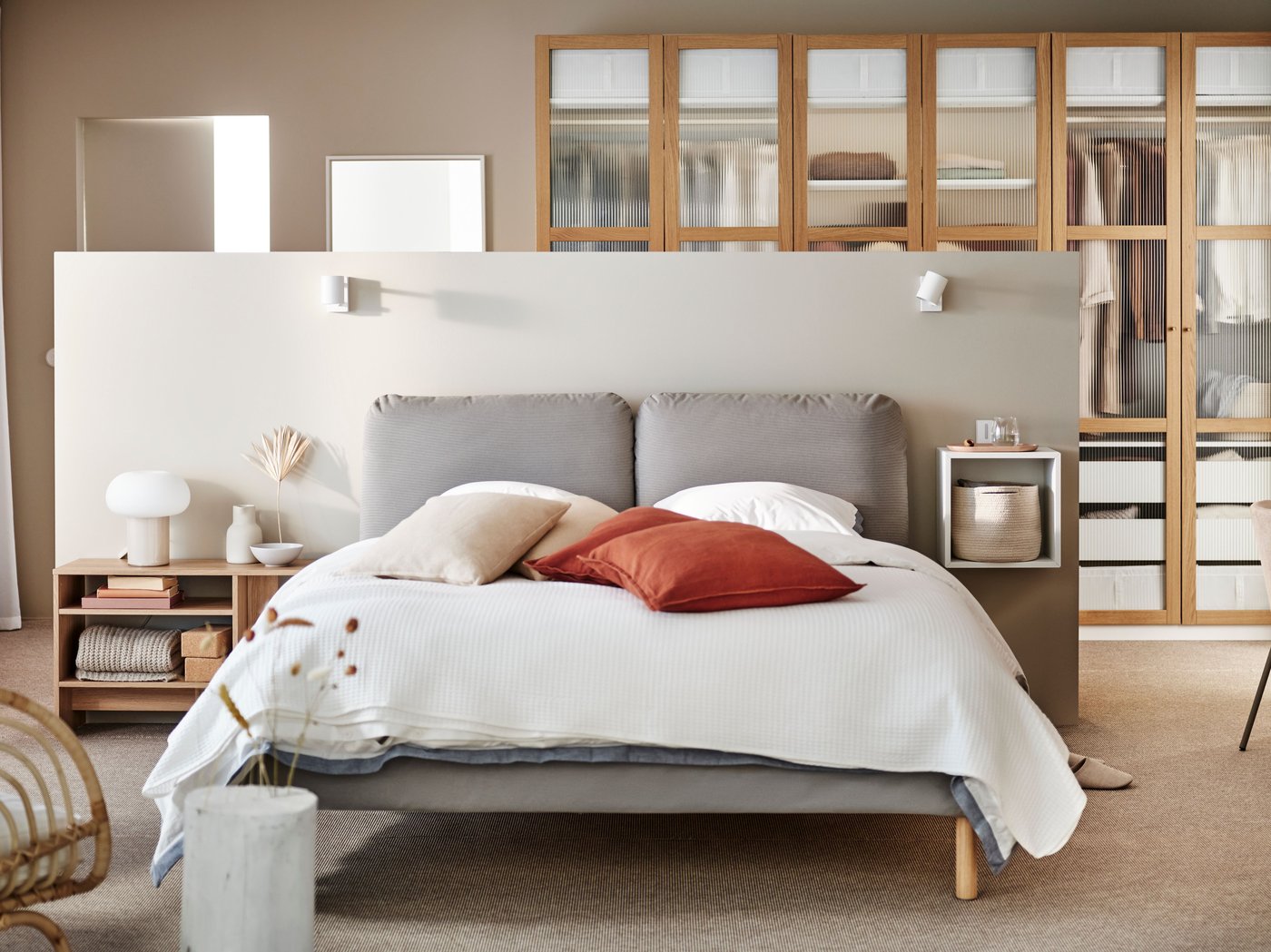 Ein Schlafzimmer mit Doppelbett, einer mittelhohen Trennwand und einem PAX Kleiderschrank dahinter.