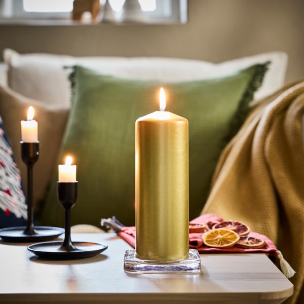 Una candela a colonna FENOMEN color oro senza profumo