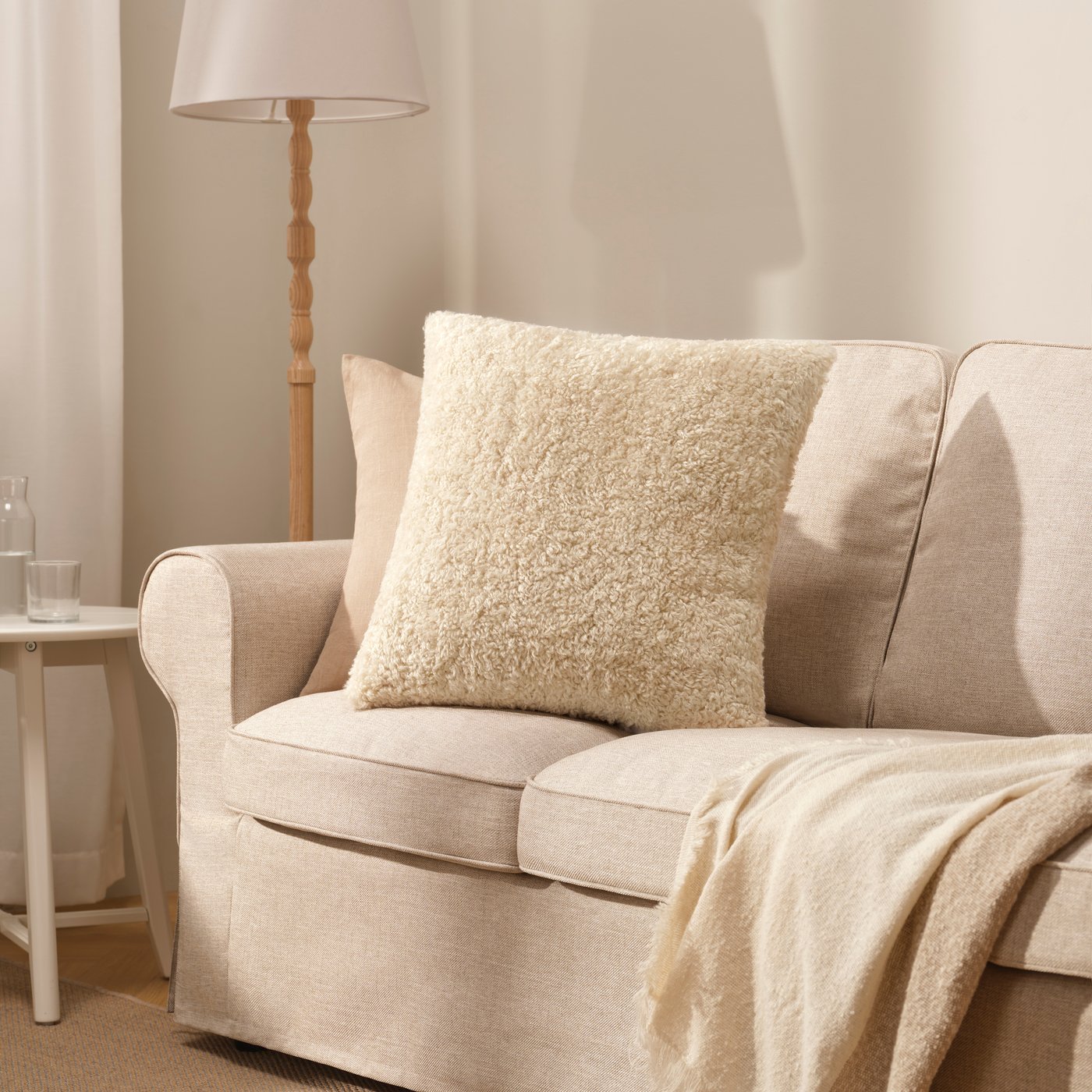 An off-white ÅSJORDFLY cushion cover