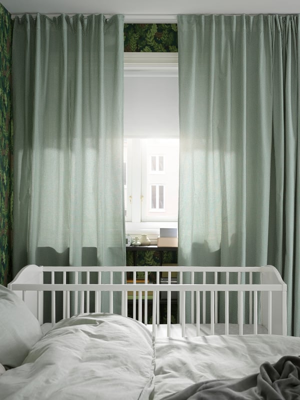  Elternschlafzimmer mit Babybett in Weiß und hellrünen Gardinen
