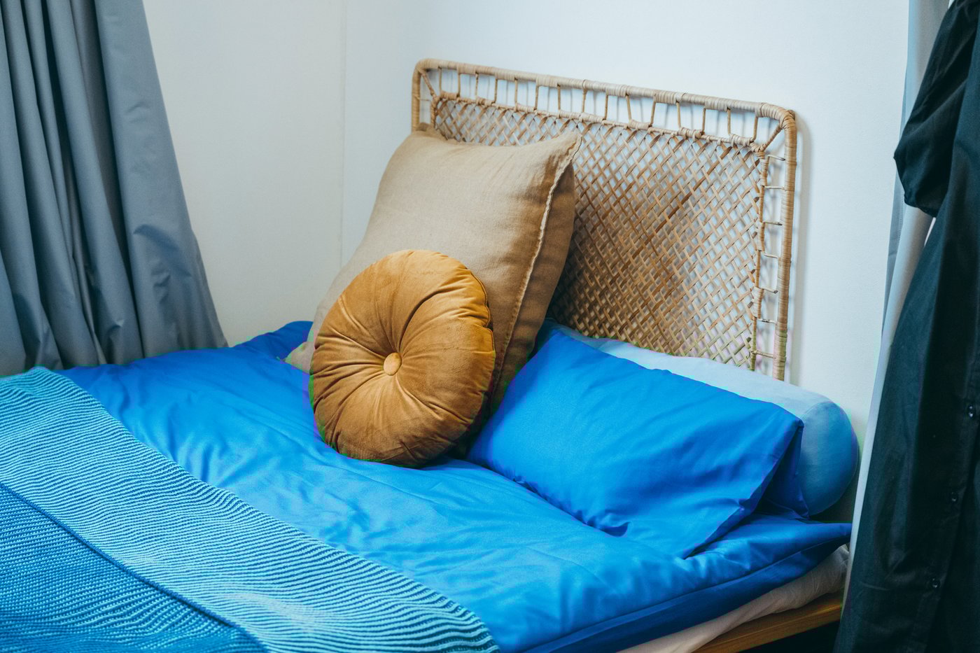 青の寝具統一されたベッドに、ベージュのクッションが2つ置かれている。