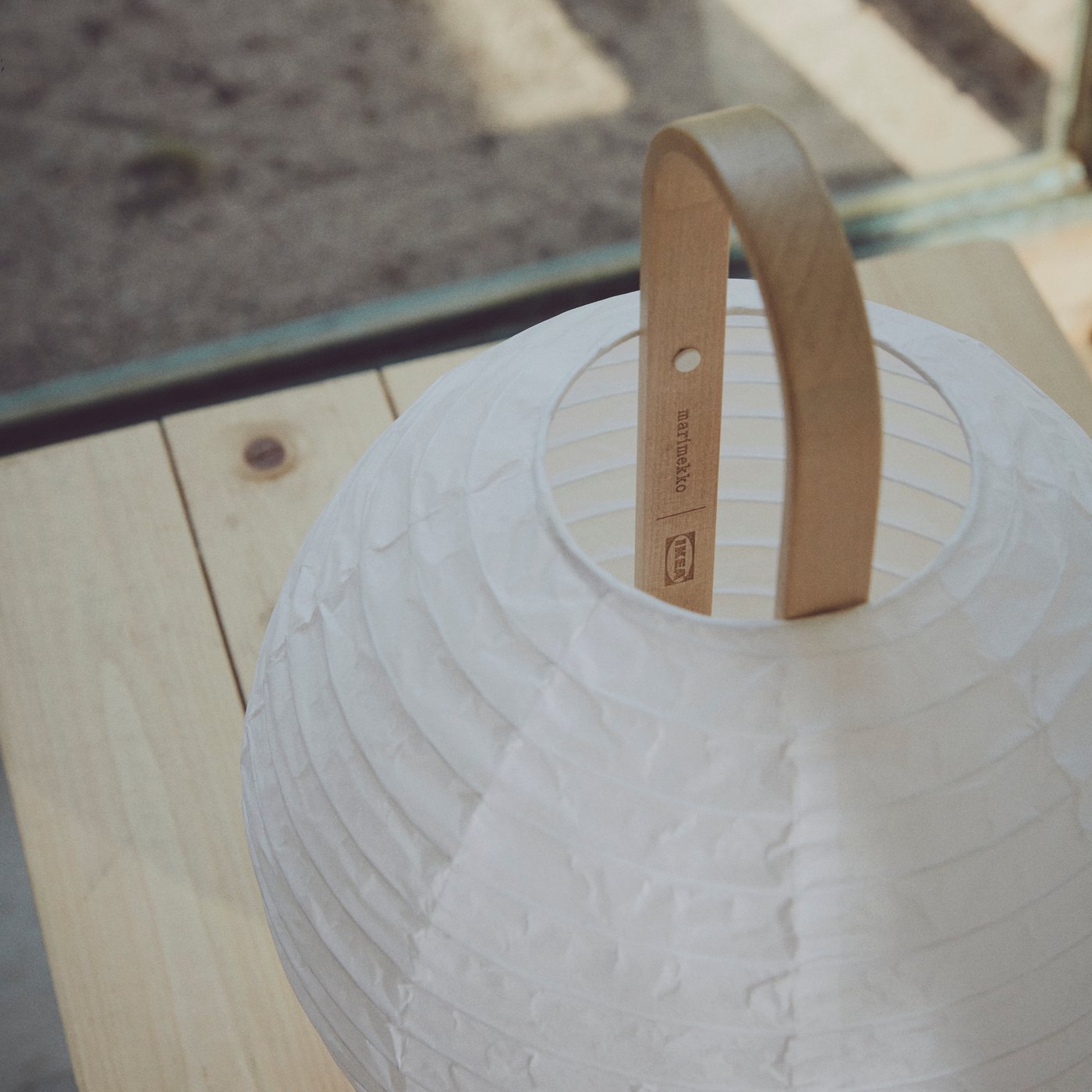 Una lampada in carta di riso bianca BASTUA con manico in legno.