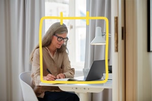 A woman writing down in front of a laptop