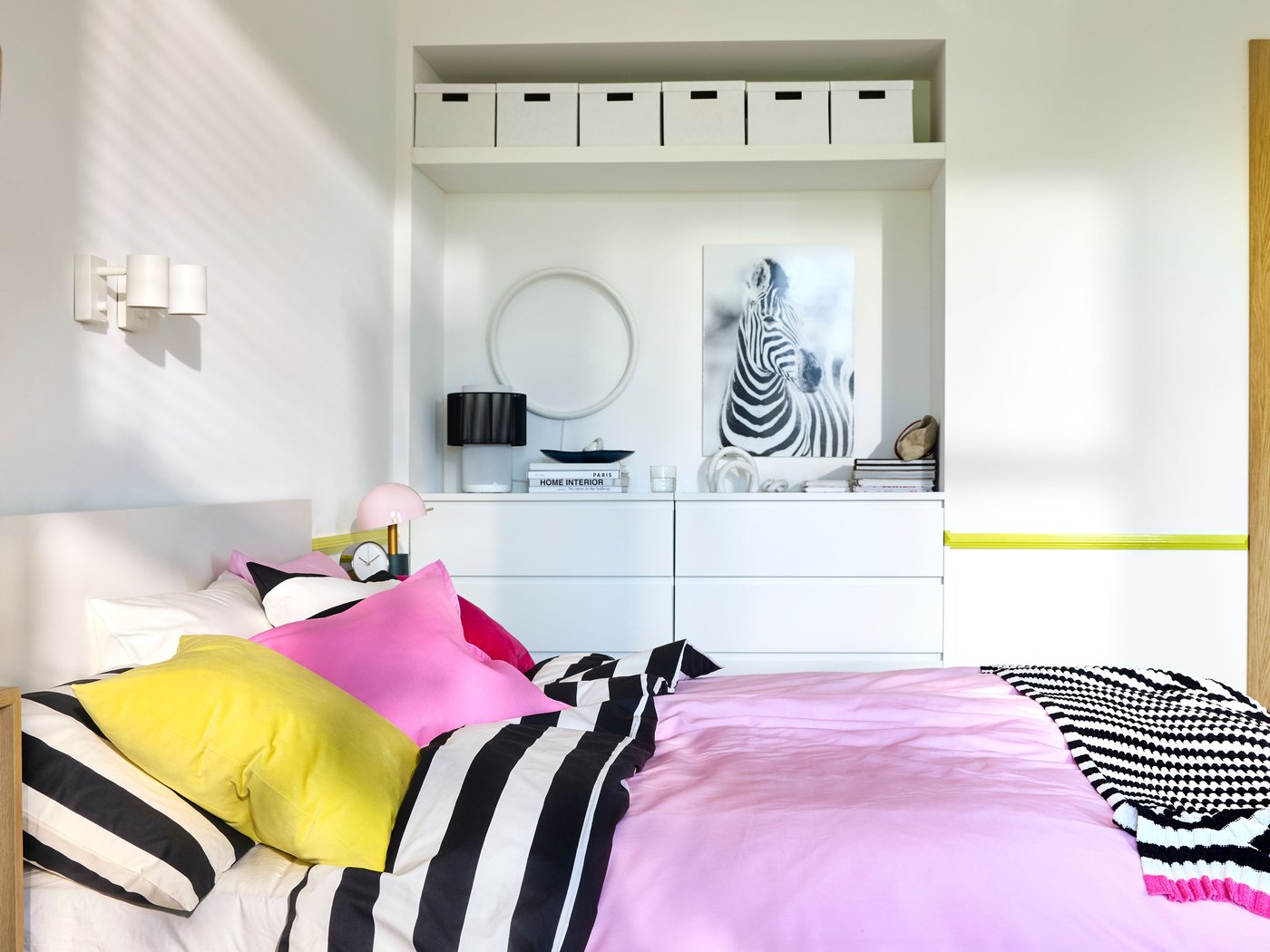 A bedroom with white walls, a PAX/STORKLINTA wardrobe and a double bed with bright pink and black/white stripe bedding.