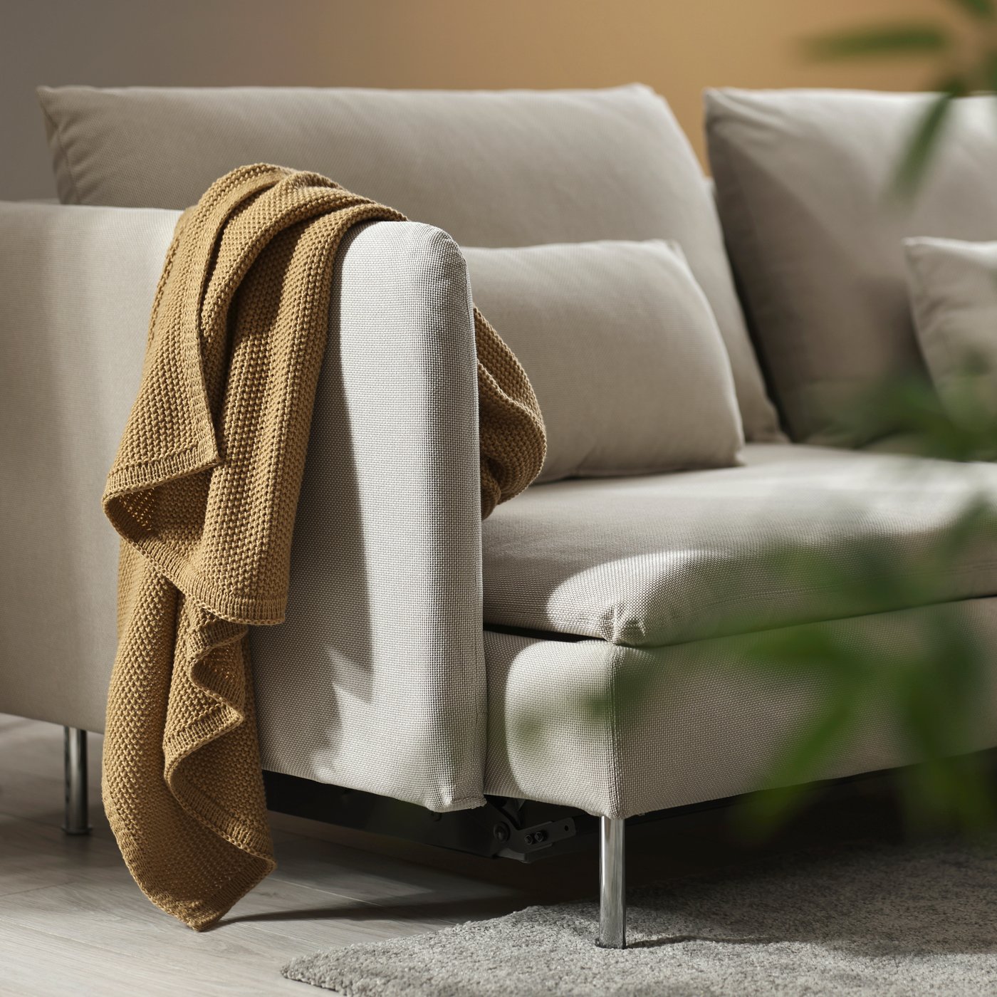 Beige SÖDERHAMN soffa med gröngul filt framför vägg i samma färg.