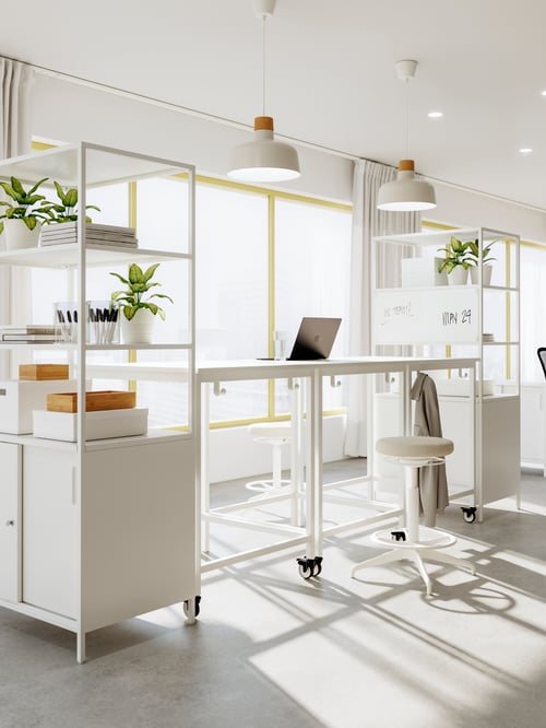 Workspace with a cabinet with sliding doors and potted plants, a table, an active sit stand support, and pendant lamps.