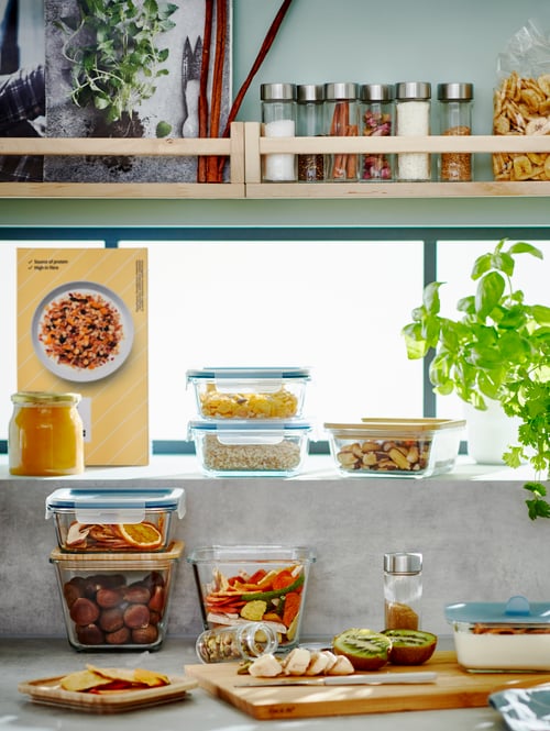 Blat de bucătărie cu polițe deasupra, pe care stau stivuite diverse caserole IKEA 365+ cu ingrediente pentru pregătirea micului dejun.