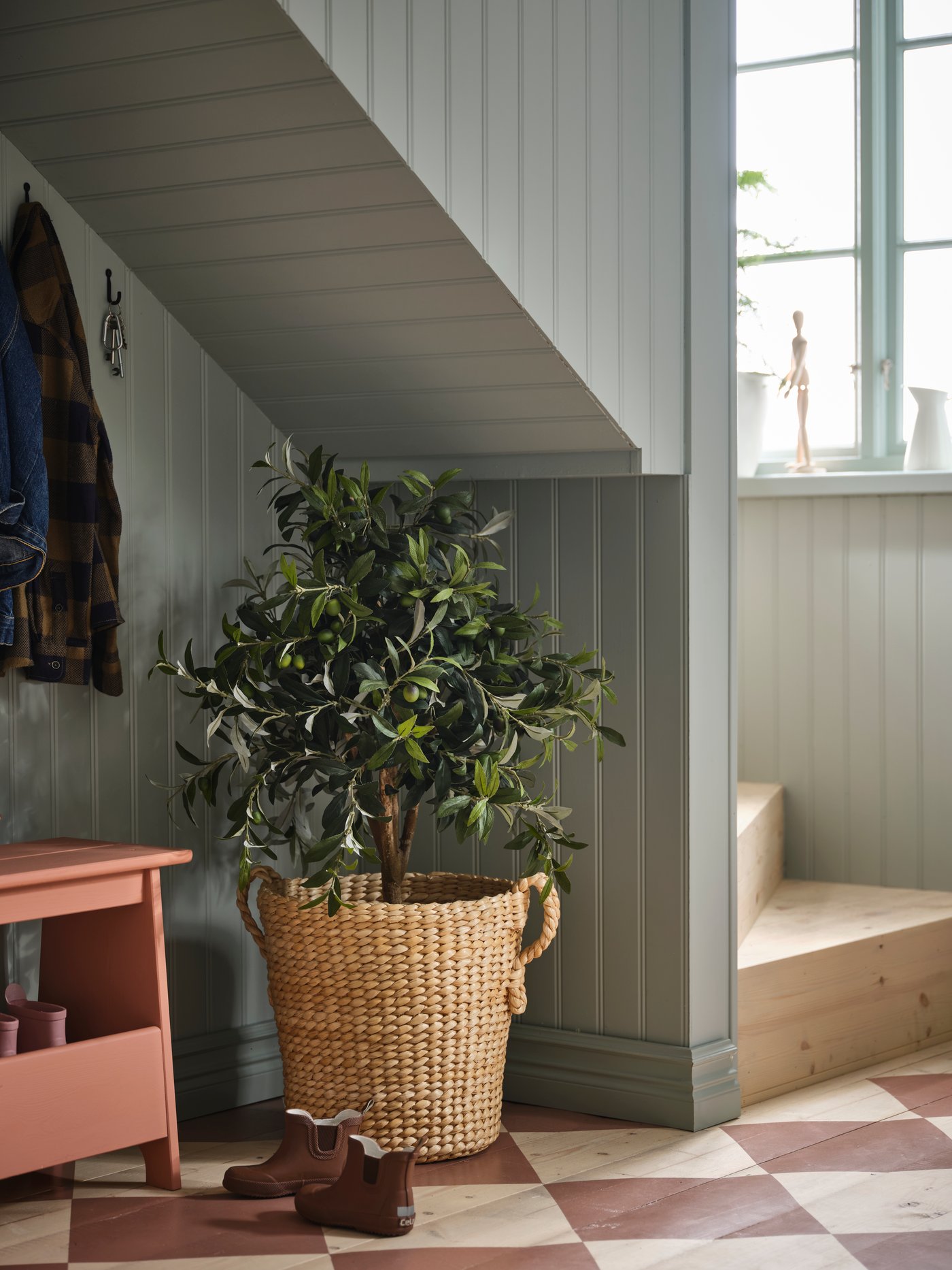 A rotan plant pot with large plant under the staircase in the hallway