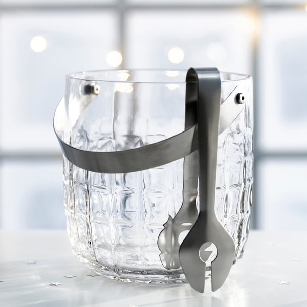 A clear glass/stainless steel FRÖJDA ice bucket with tongs