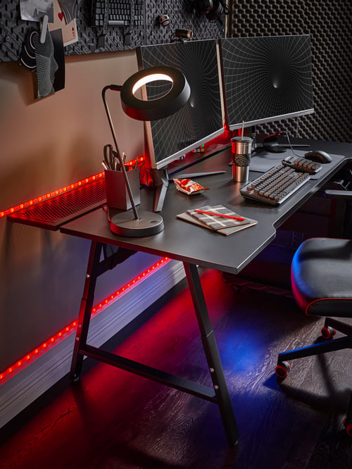 Workspace with a rectangular gaming desk supporting a gaming mouse pad, a mouse bungee and a LED work lamp.