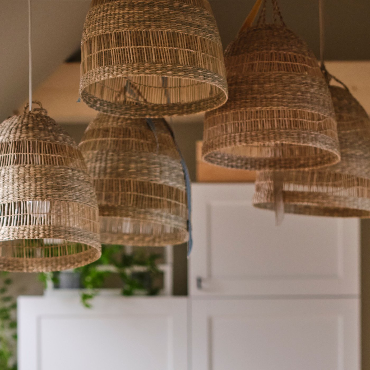 Fem handgjorda TORARED lampskärmar i säv hänger i sovrummet.
