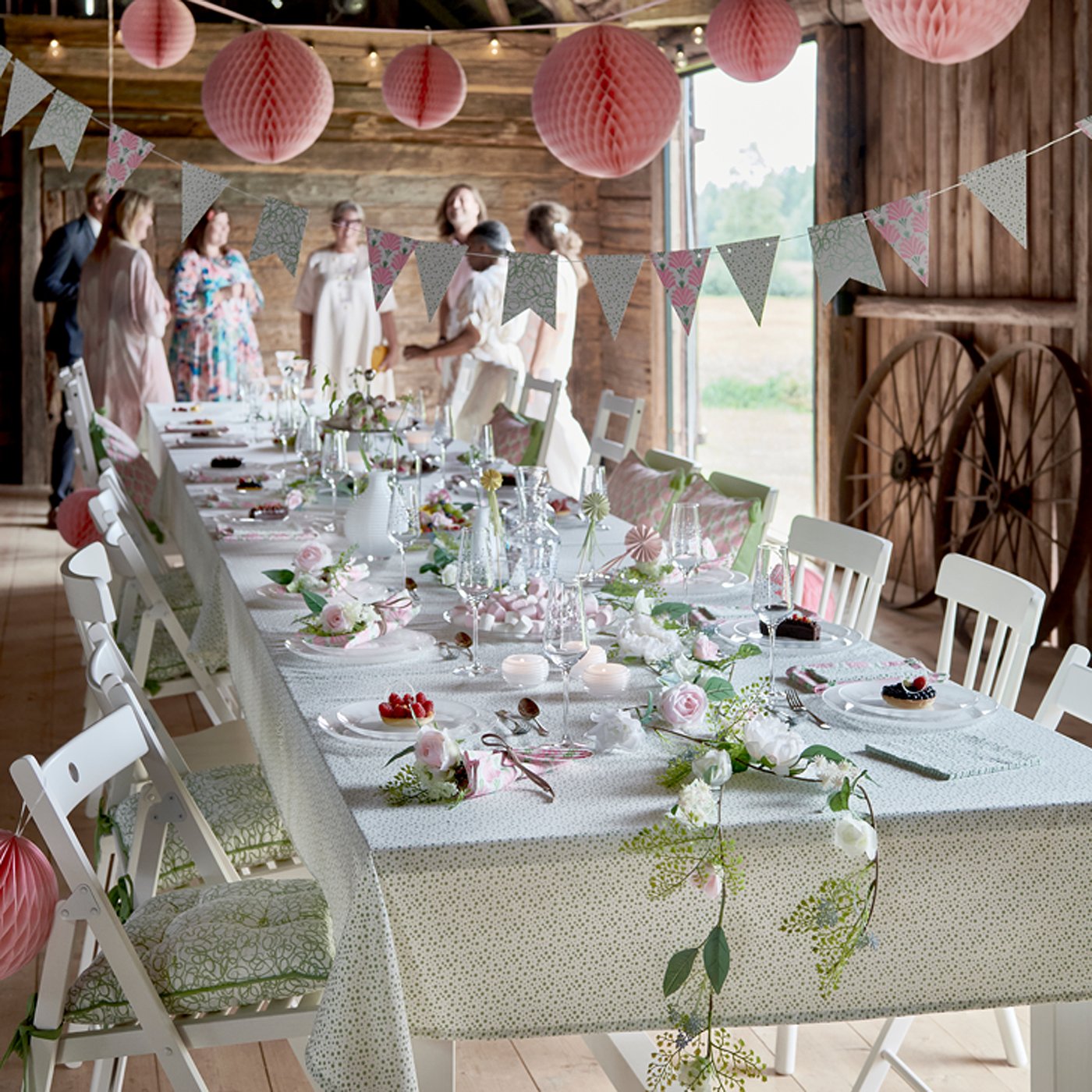 Biały rozkładany stół NORDVIKEN w szkopie, przy którym stoją ludzie.