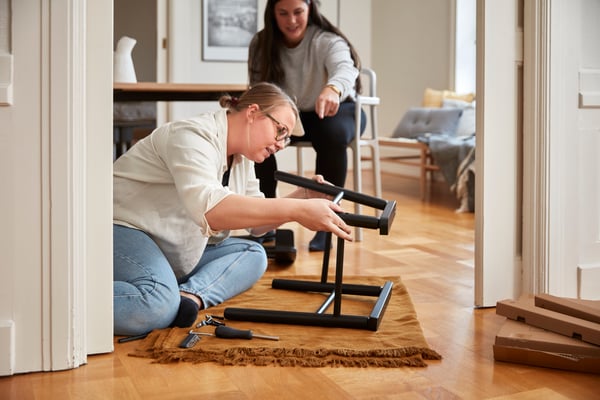 Two women building furniture in their home. 