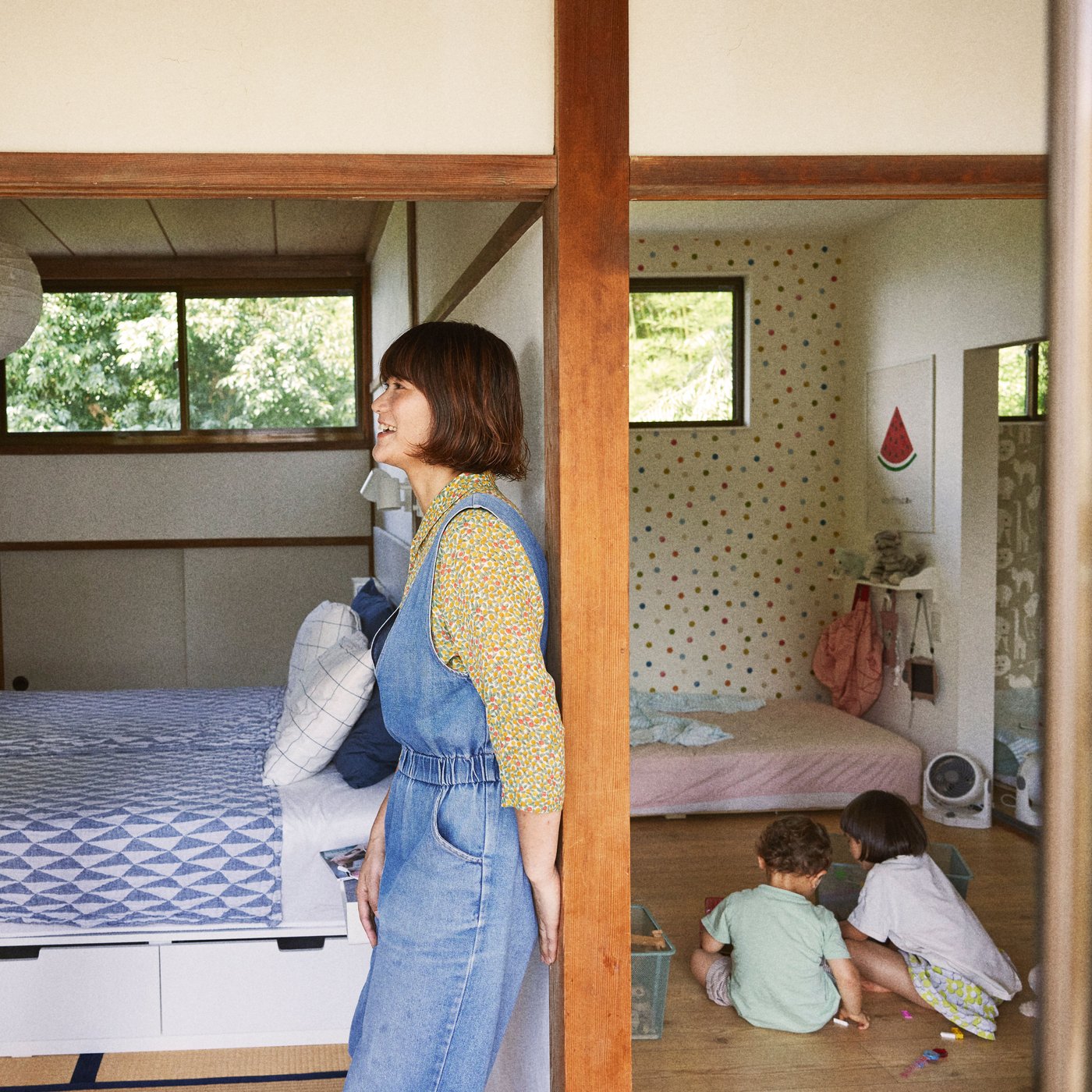 A woman  having a dialogue inside a room and kids playing on the floor. 