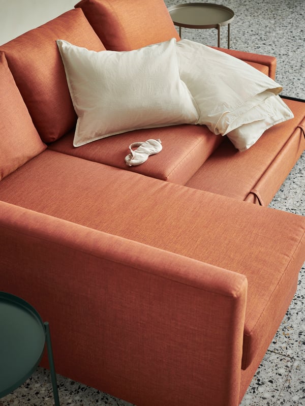 A picture from above of FRIHETEN sofa with a few beige cushions and the extra mattress sticking out from underneath.