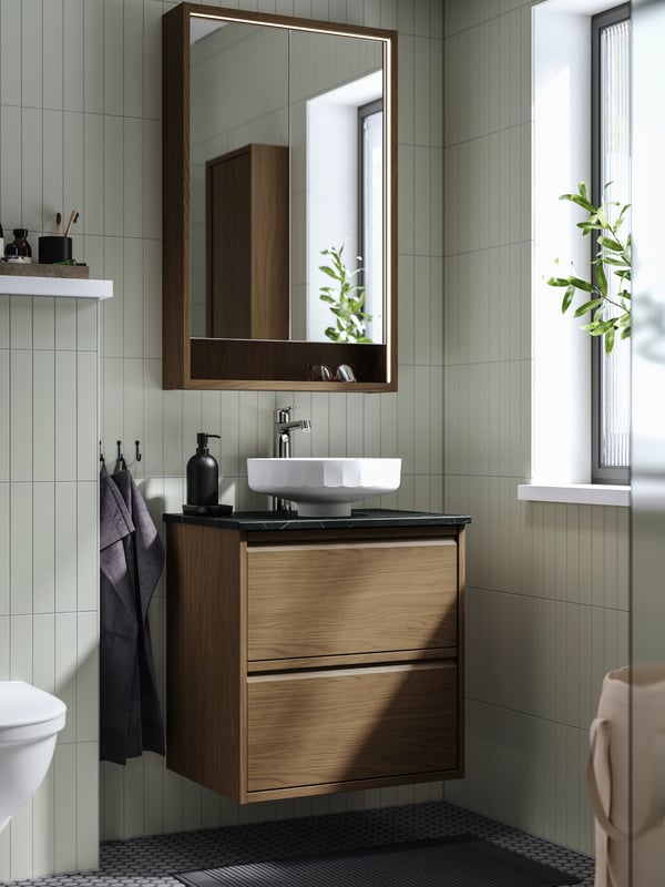 Ein LERSJÖN Waschbeckenunterschrank mit Schubladen/Waschbecken/Wasserhahn in brauner Eichenoptik/schwarzer Marmoroptik.