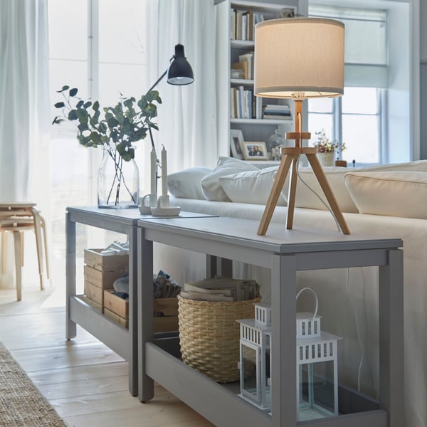 Eine LAUTERS Standleuchte steht auf einem Regal hinter einem hellen Sofa.