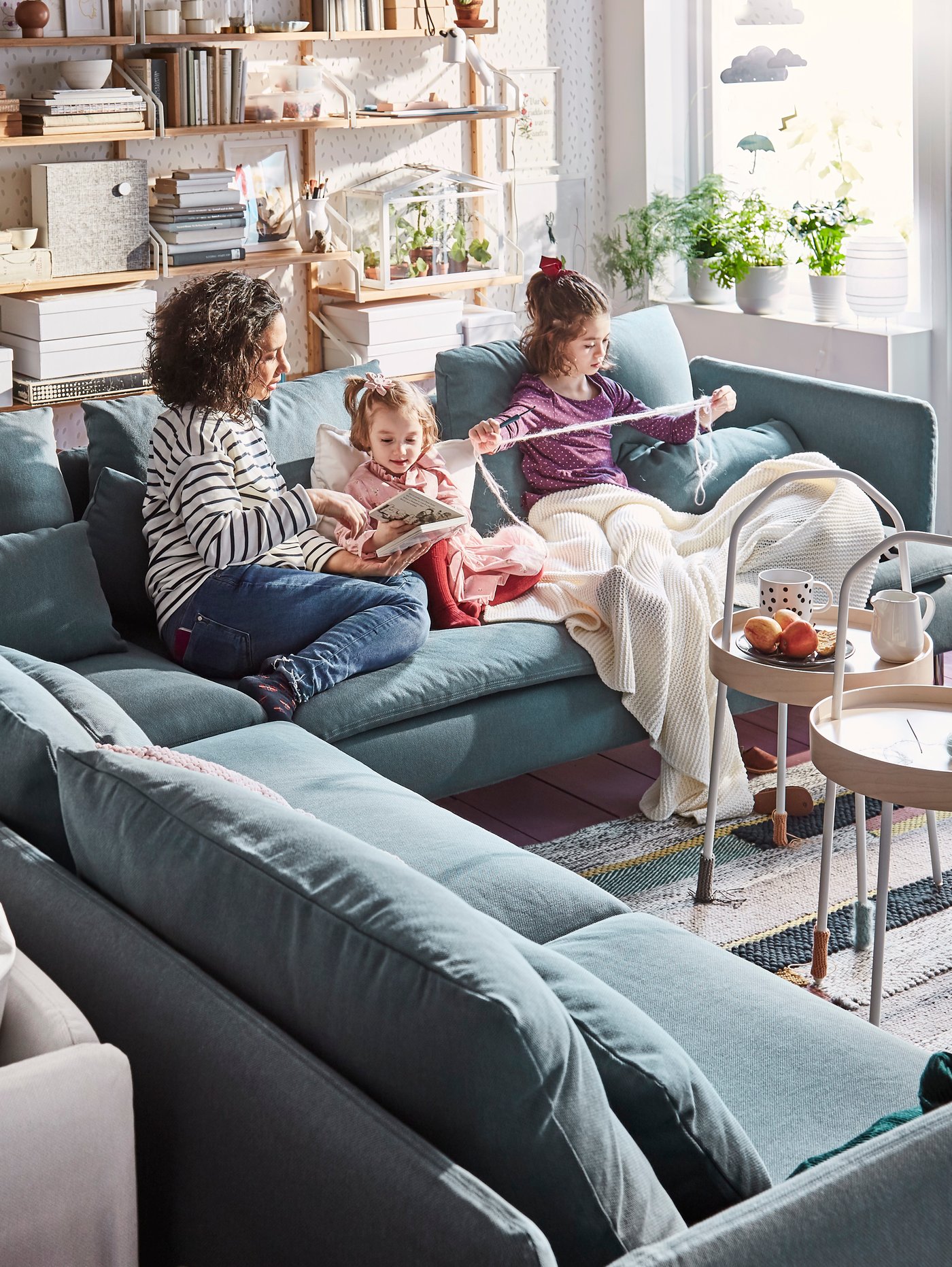 A family is sitting on a large blue SÖDERHAMN sofa in the living room.
