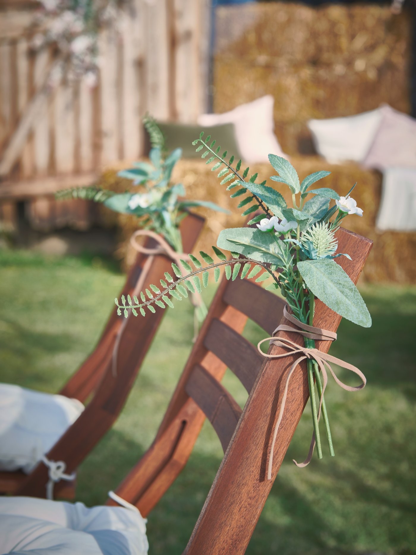 Mazzetti di fiori e foglie SMYCKA legati con nastri beige decorano le sedie pieghevoli ÄPPLARÖ in un party all’aperto - IKEA