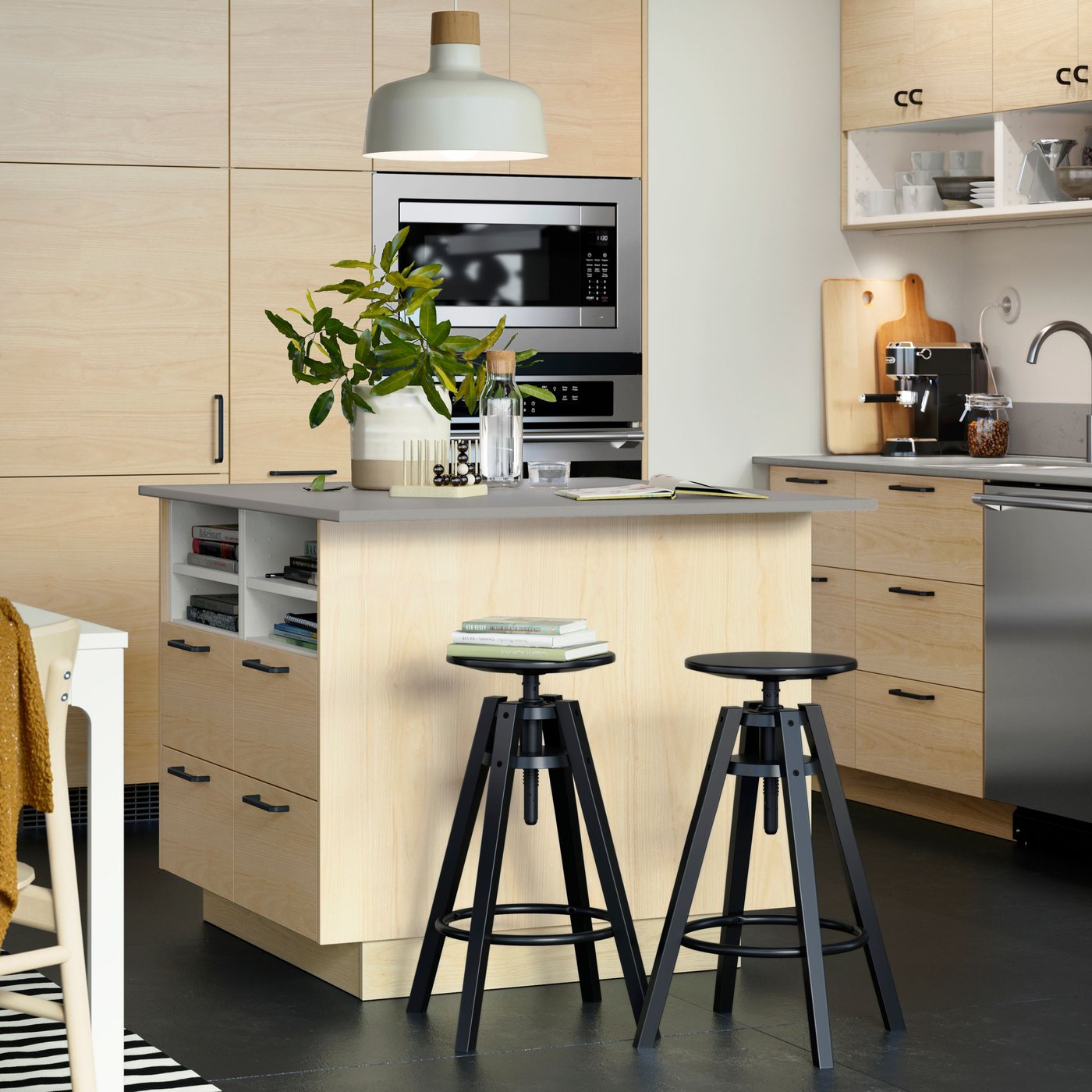 A large kitchen island with ASKERSUND fronts in light ash effect has a white pendant lamp above it and two black stools.
