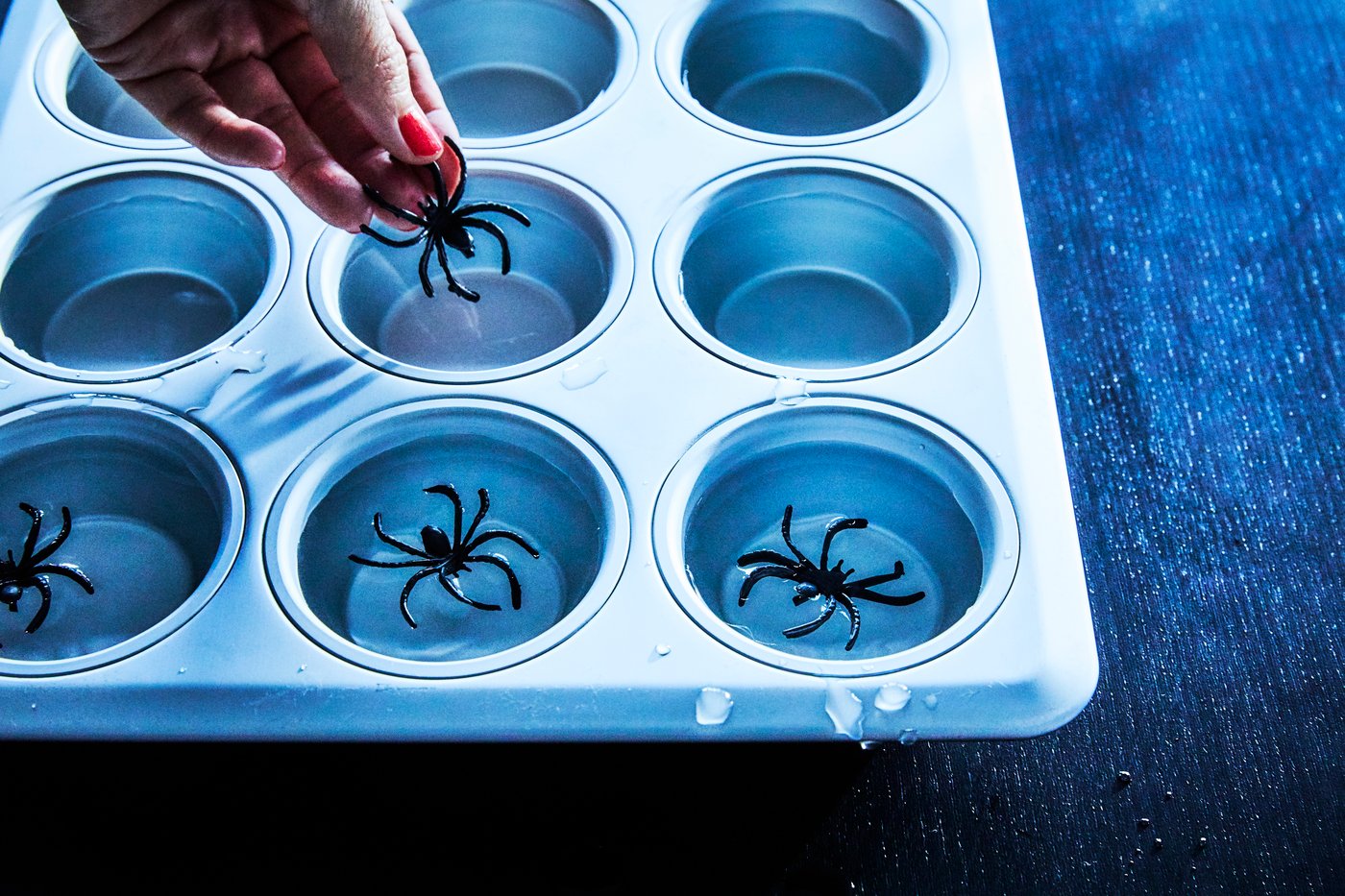 En person lägger ner en plastspindel i en muffinsform.