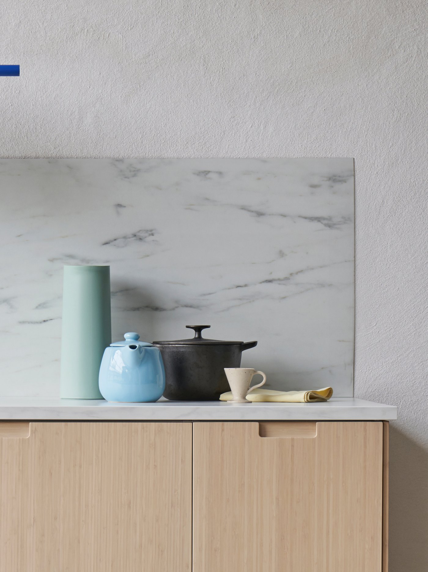 Holzküche mit blauer Teekanne und Küchenrückwand in Marmoroptik