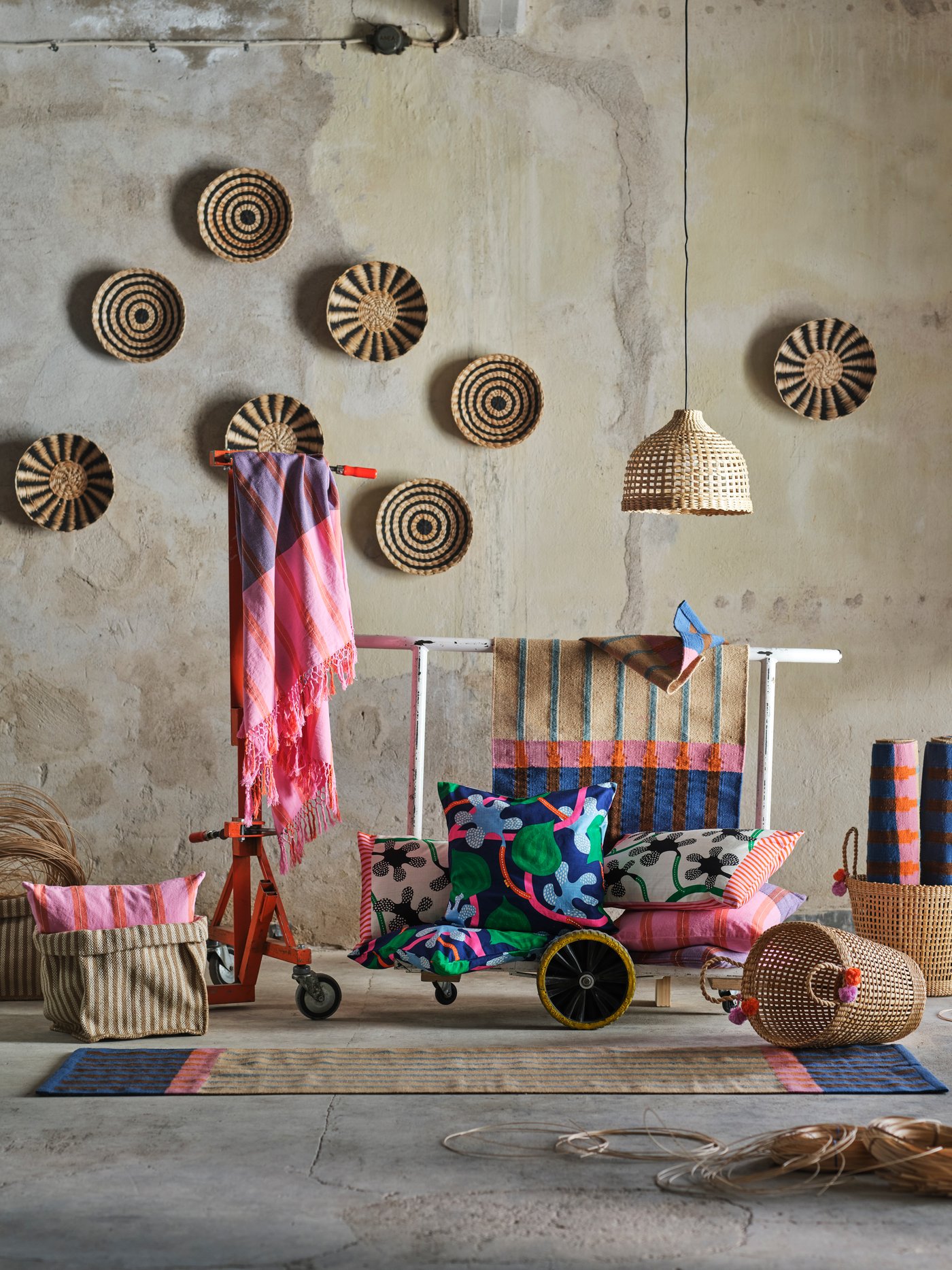 La collection MÄVINN est présentée dans un espace d'aspect industriel. Les fibres naturelles se mêlent aux textiles roses, verts et bleus.