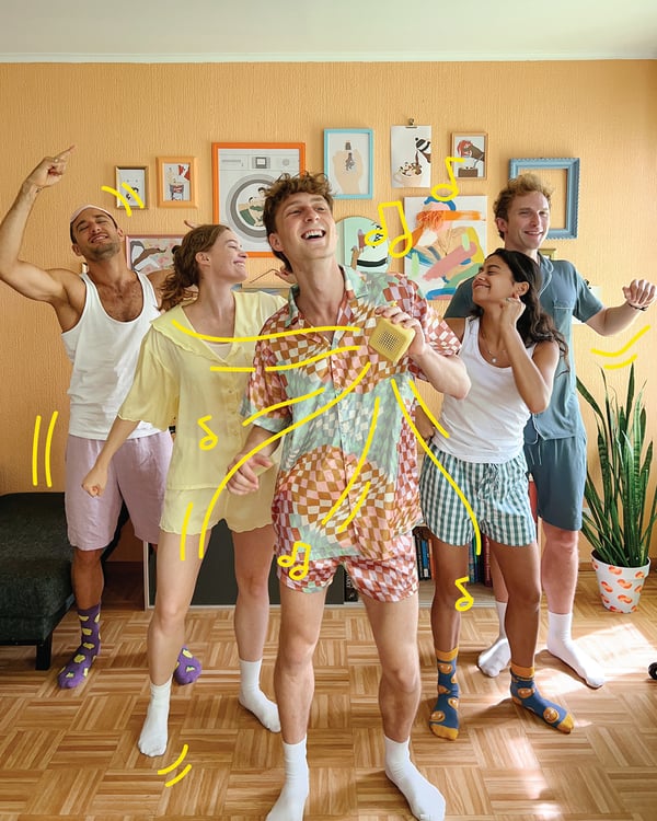 Five people dancing in a room with orange walls.