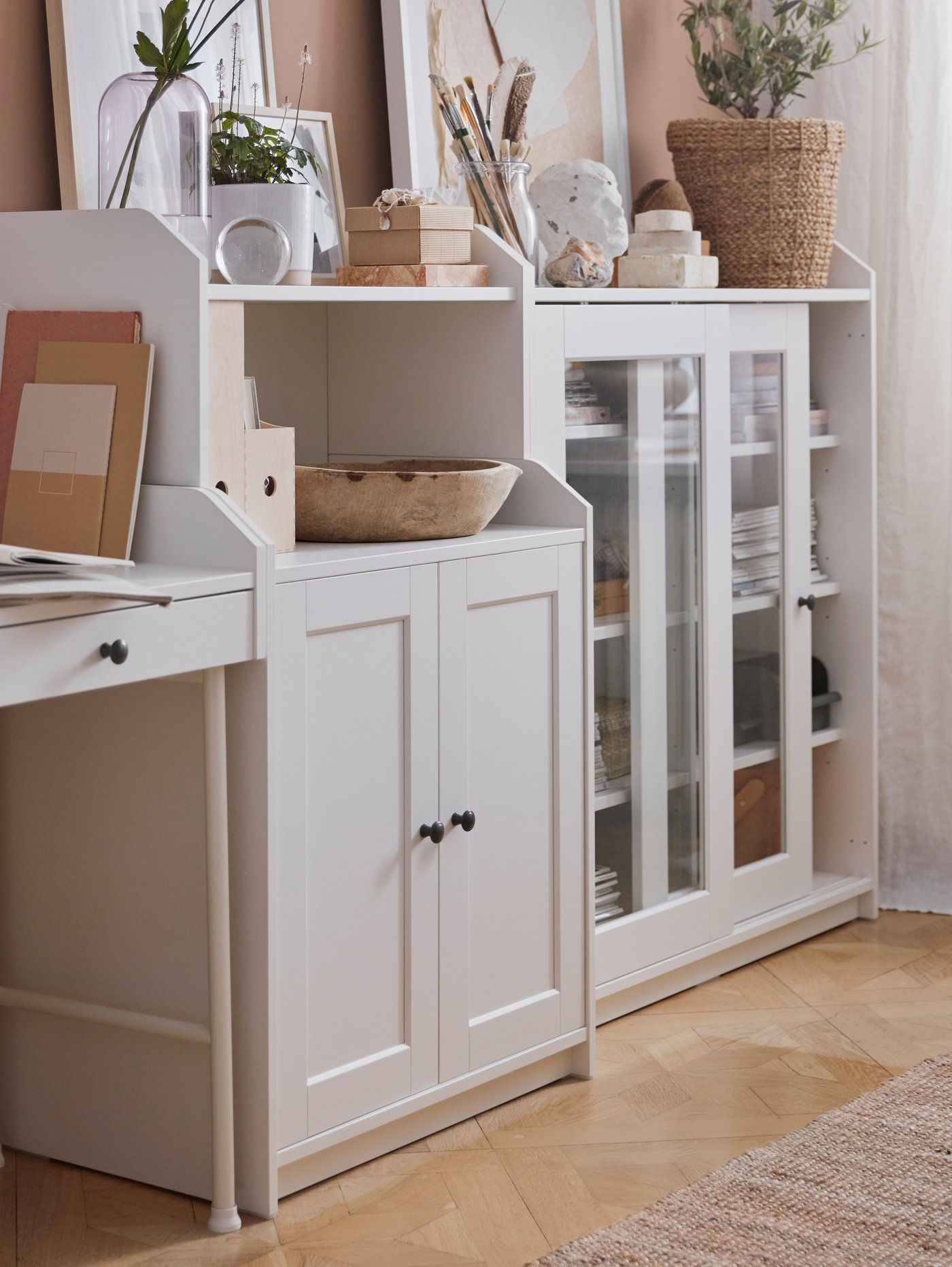 Espacio de trabajo moderno en el hogar donde hay un armario blanco con dos puertas, un escritorio rectangular, una vitrina y un jarrón.