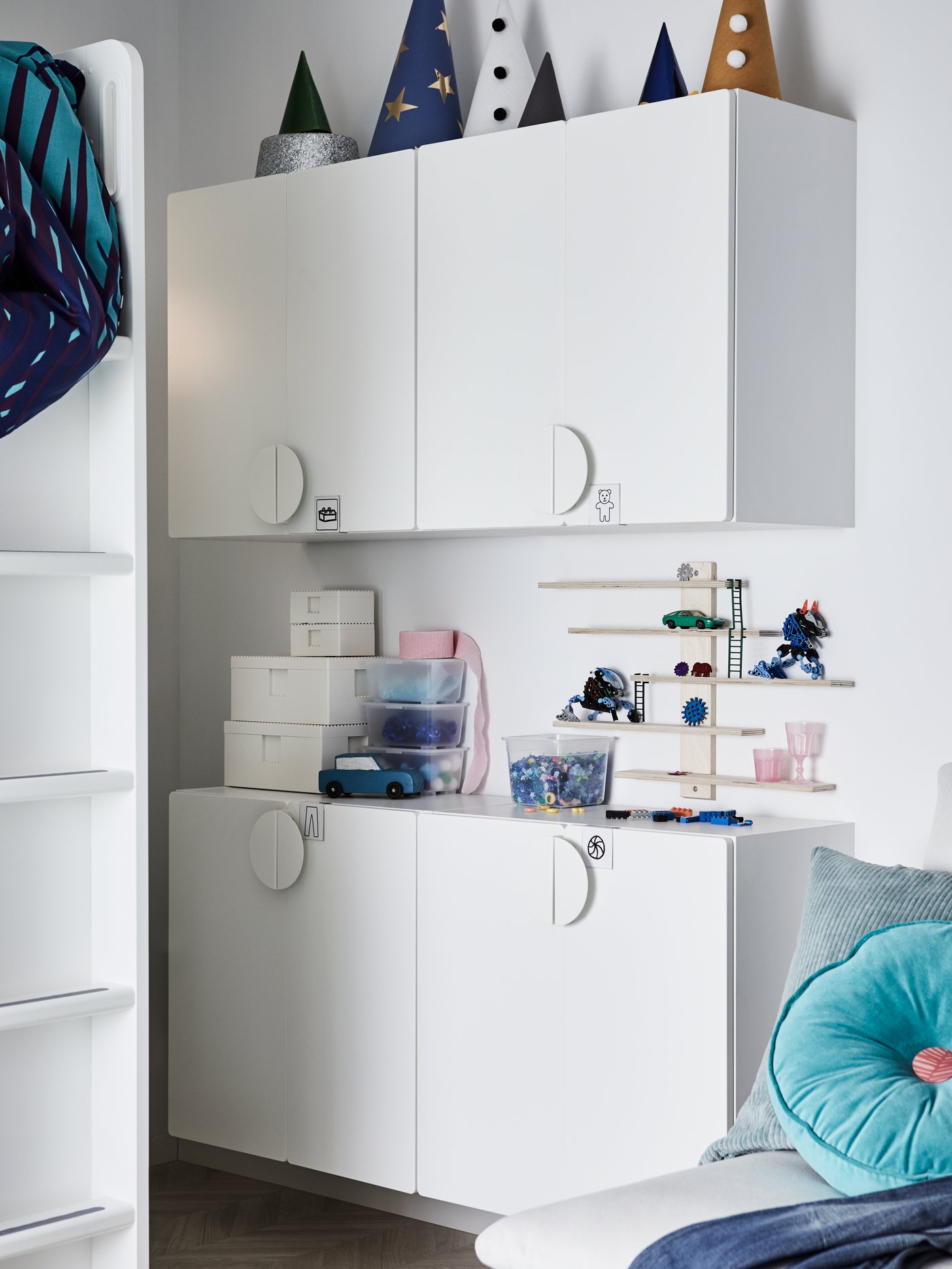 Op vier witte SMÅSTAD wandkasten staan verschillende dozen en andere voorwerpen, en we zien ook nog de ladder van een hoogslaper.