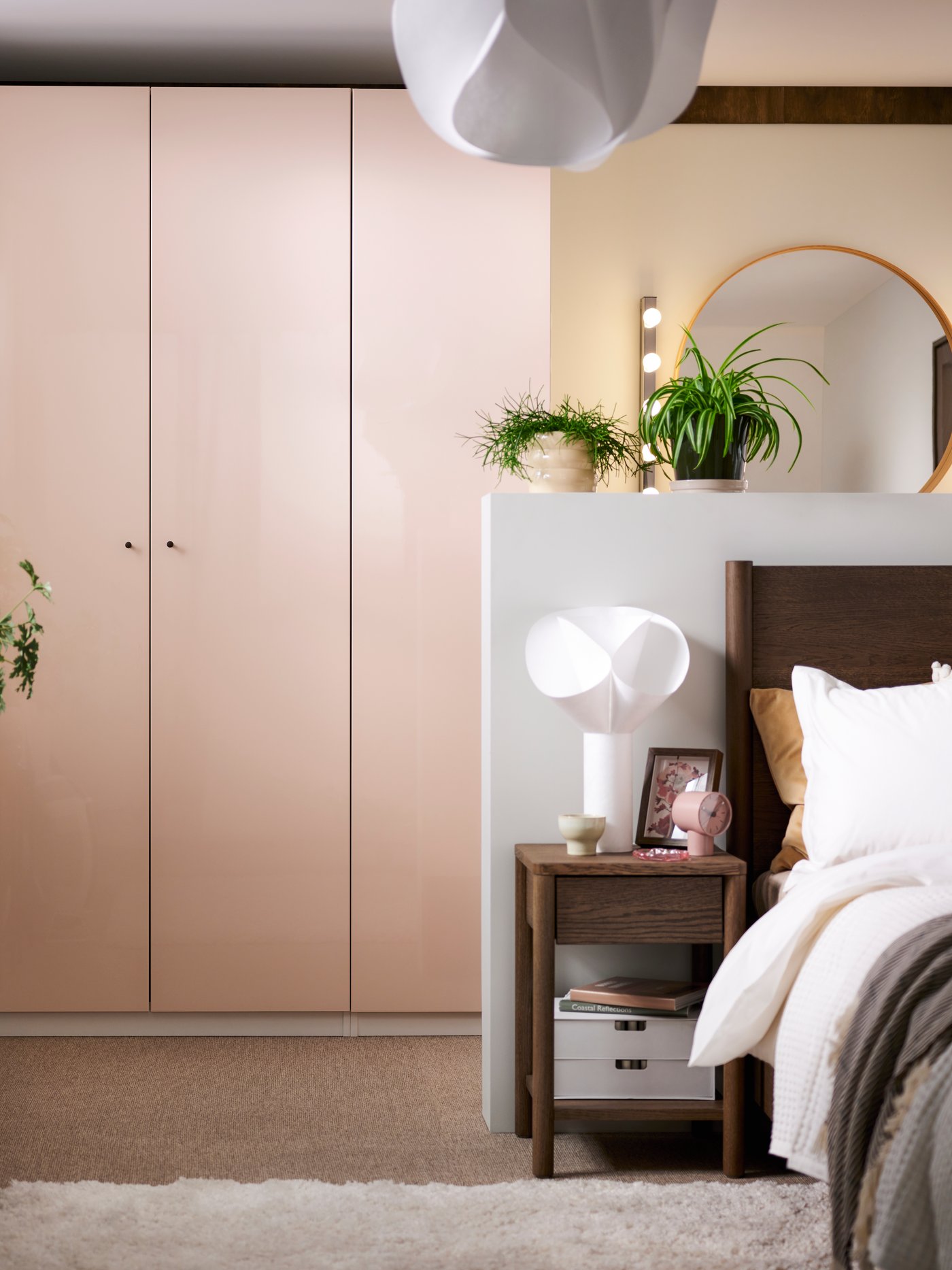 A sunny bedroom with a brown stained oak veneer TONSTAD bed in front of a PAX wardrobe with light orange FARDAL doors.