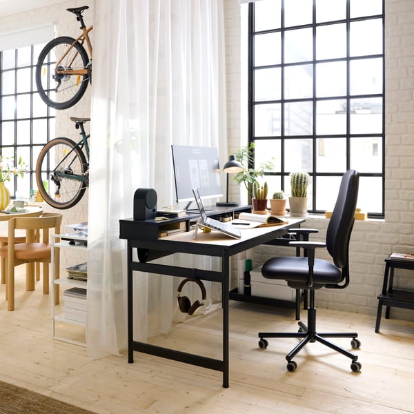 A black MULLSJÖ desk with an oak top and a black Bluetooth speaker on the top unit. In front sits a SMÖRKULL office chair.