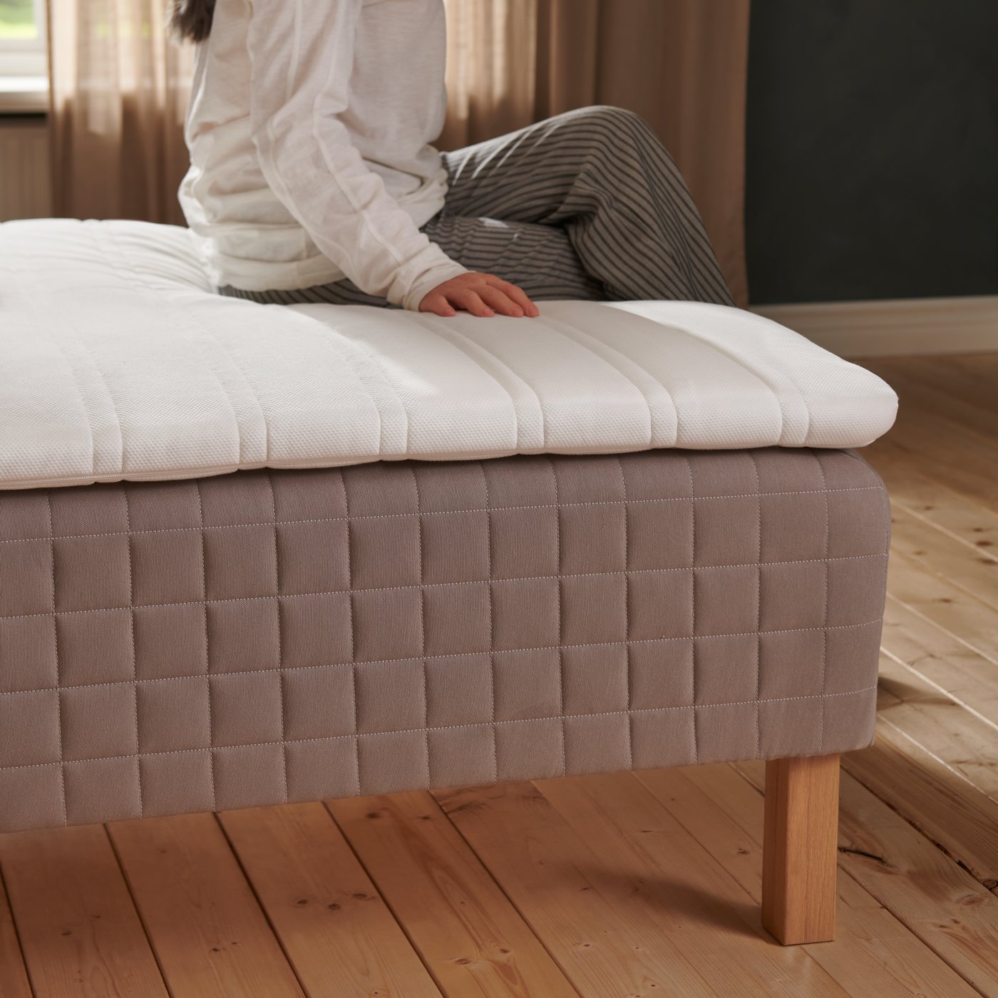 Udsnit af person der fører hånden over en topmadras.