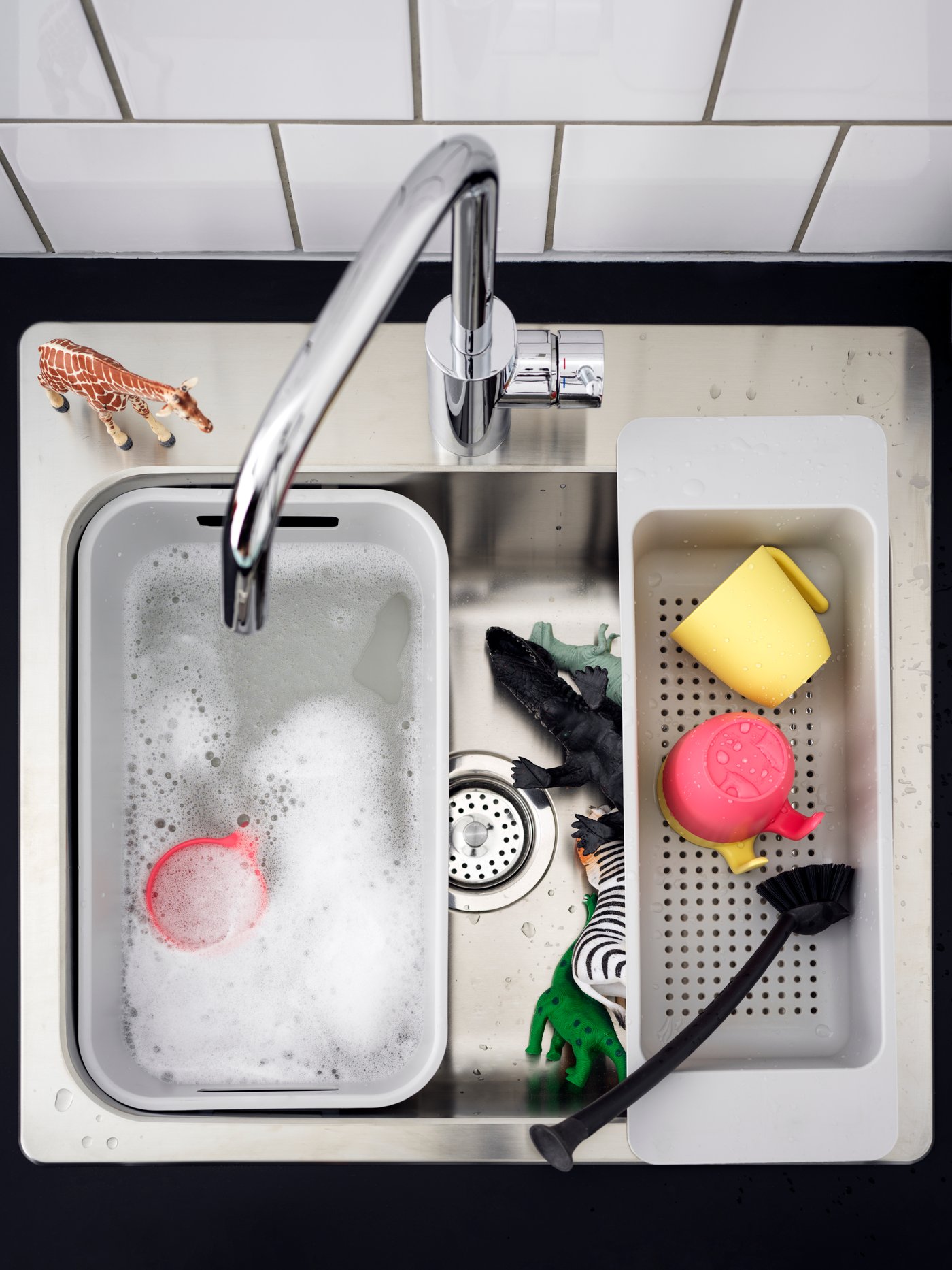 A LÅNGUDDEN sink together with a colander, a washing-up bowl, and some plastic animals and pink and yellow cups.