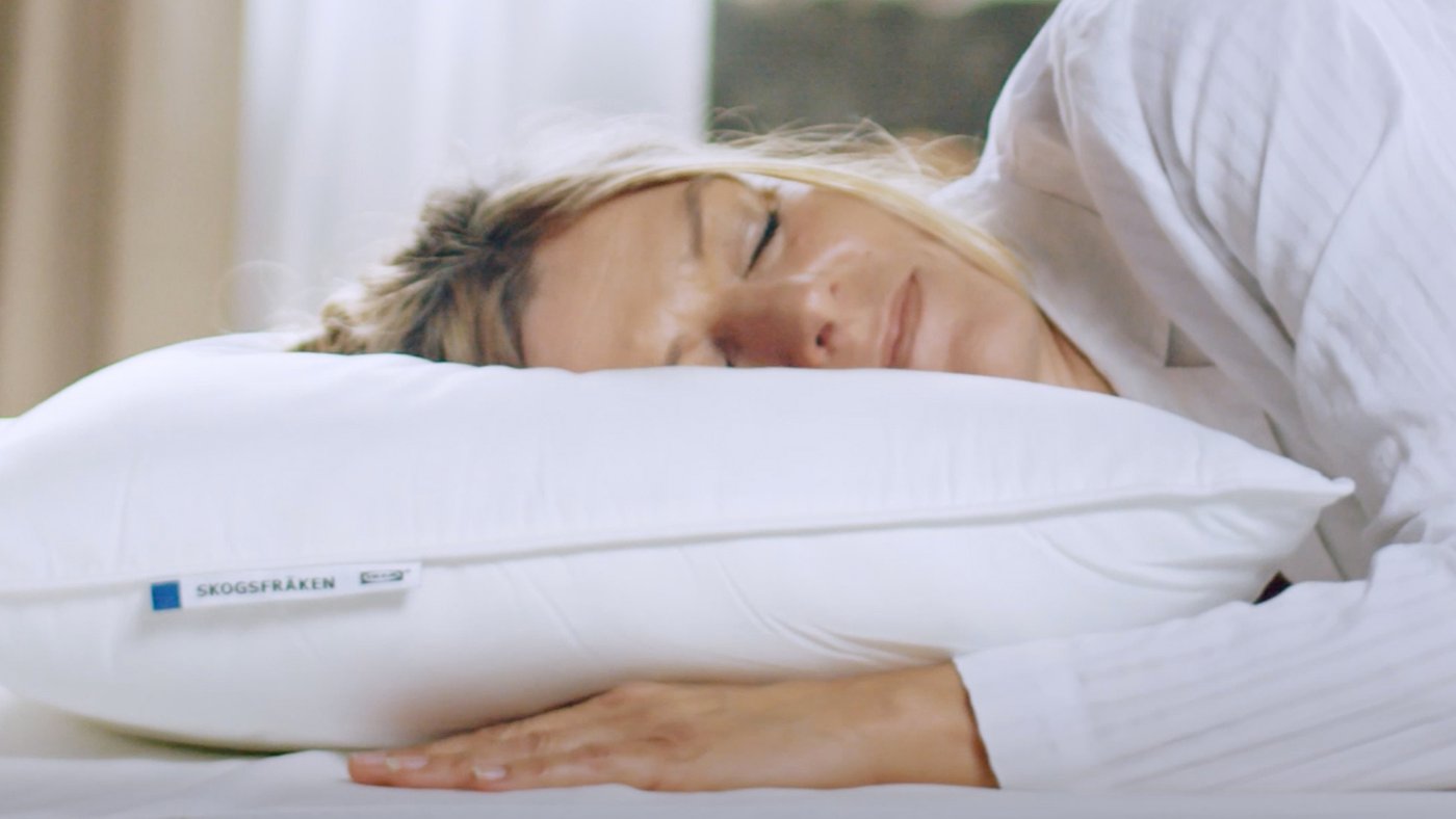 A person asleep on their side with their head on a high SKOGSFRÄKEN pillow that has no pillowcase on it.