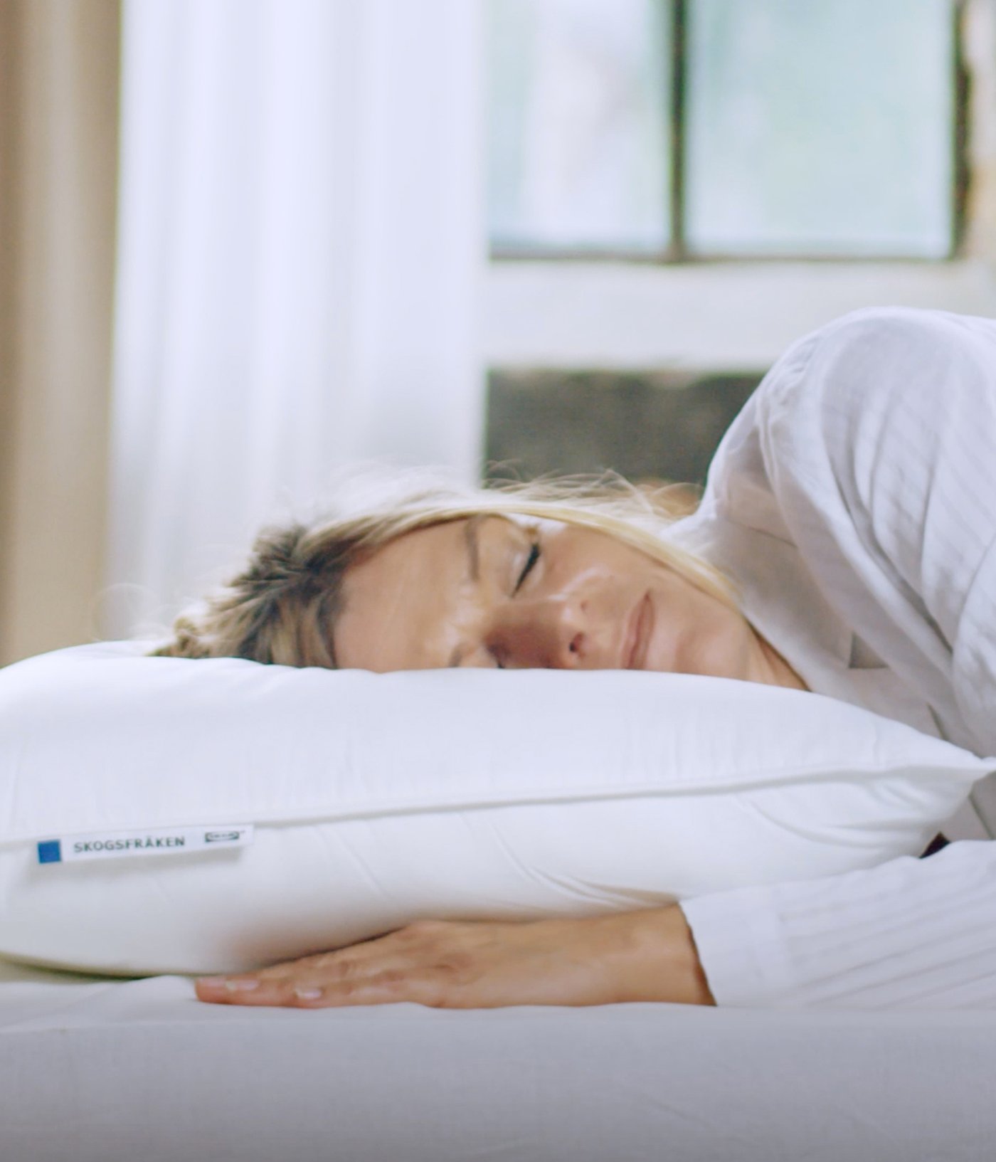 A person asleep on their side with their head on a high SKOGSFRÄKEN pillow that has no pillowcase on it.
