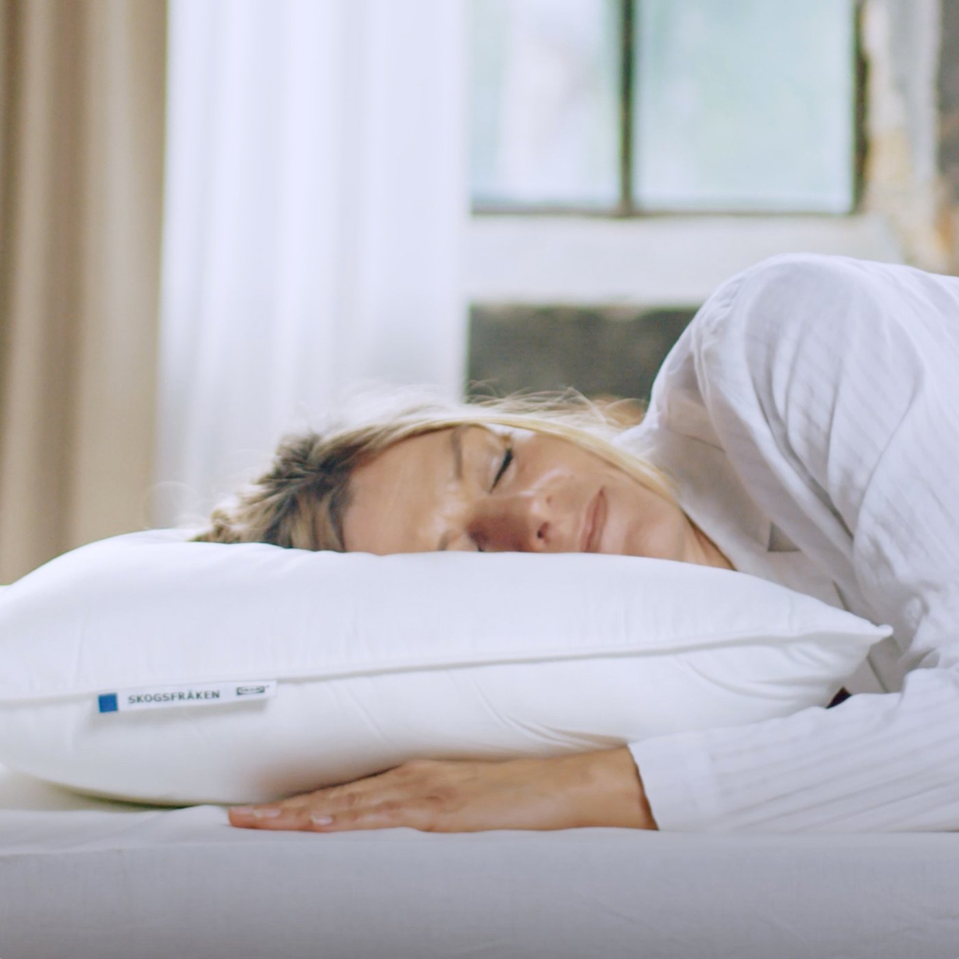 A person asleep on their side with their head on a high SKOGSFRÄKEN pillow that has no pillowcase on it.