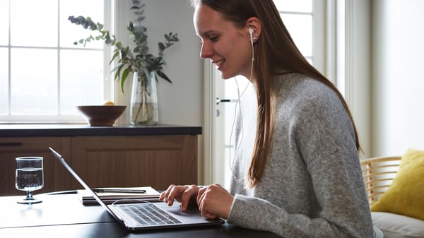 Una donna guarda un computer portatile e legge.