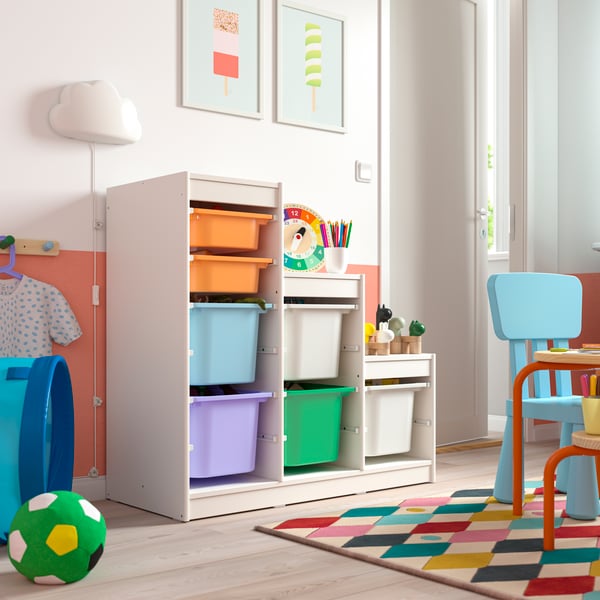 Children’s white toy storage unit with colorful plastic bins in a playroom