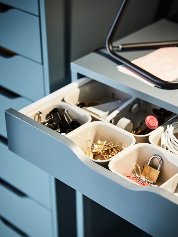 Close-up on the open drawer of the ALEX desk in grey-turquoise, showing drawer lined with NOJIG organisers with stationery.