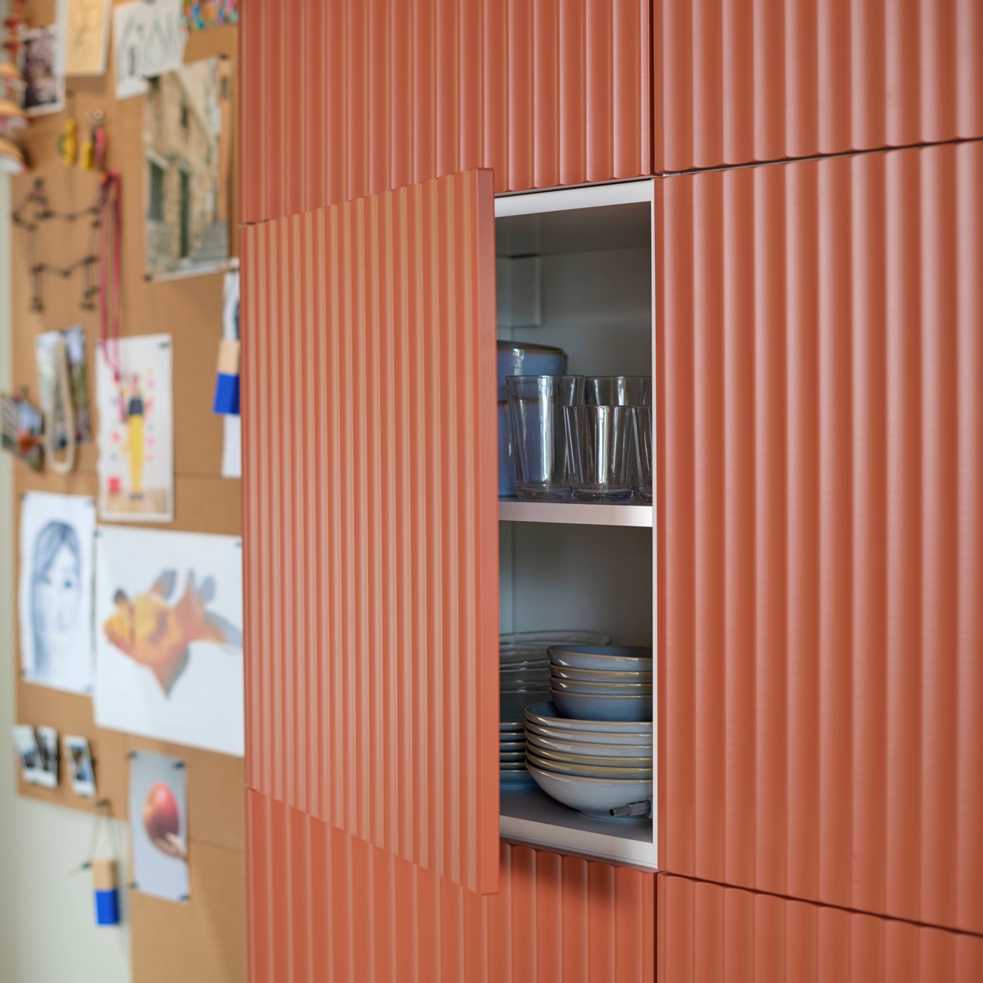 Een keukenkast is afgewerkt met een TERRSJÖ accentdeur met een roodbruin golfmotief. De deur staat open. In de kast zitten keukenspullen.