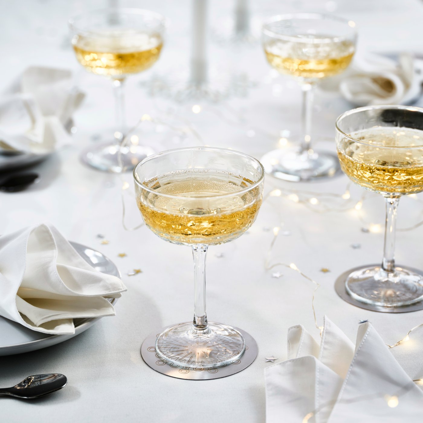 Fyra FRÖJDA champagneglas på en vit duk.