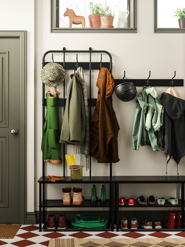 NIPÅSEN coat rack and benches full of shoes, jackets, hats, helmets and some garden tools, all in a neat order.