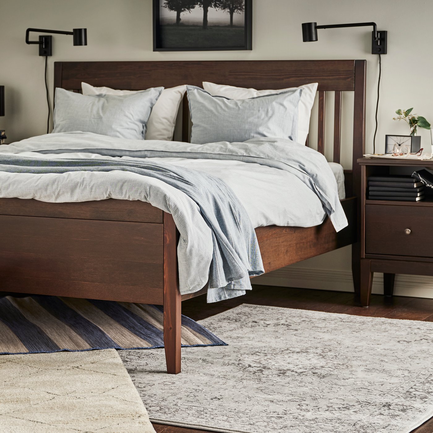VRENSTED, VEDBÄK und TVERSTED Teppiche unter einem IDANÄS Bettgestell mit der BERGPALM Bettwäsche und einem grauen Plaid.