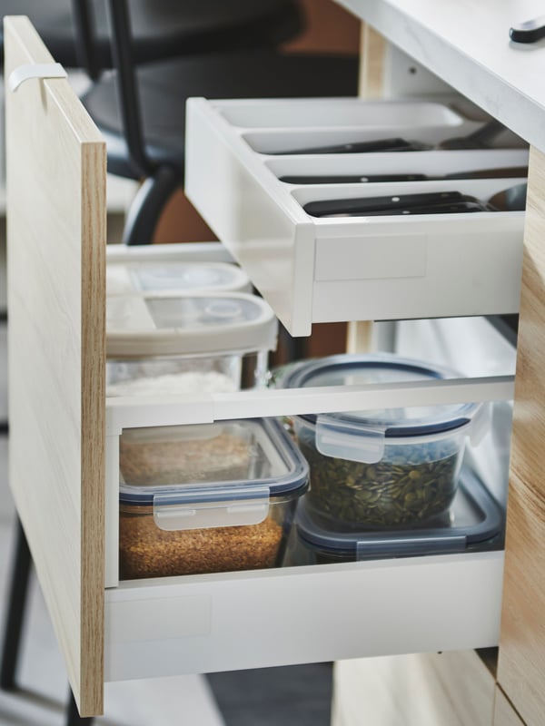 Un primo piano di un frontale aperto che svela dei contenitori IKEA 365+ e un piccolo cassetto UPPDATERA per posate.